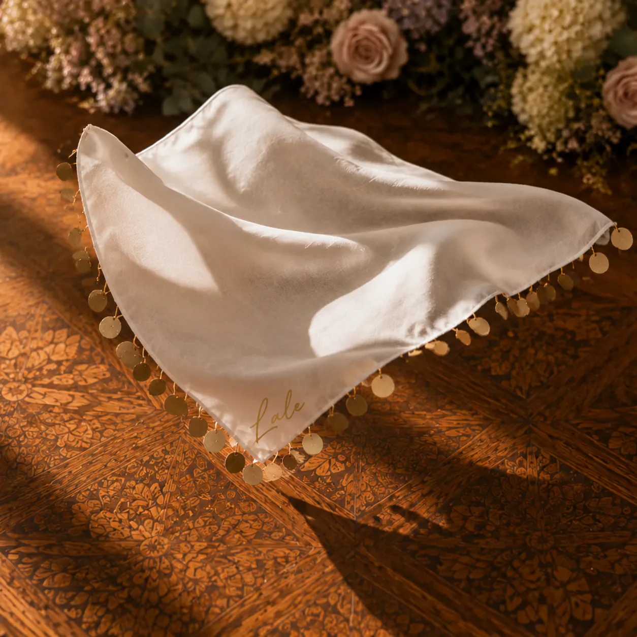 Ein weißes Halay-Tuch mit goldenen Talern liegt auf einem Holztisch, in der Ecke steht in Gold der Name Lale.